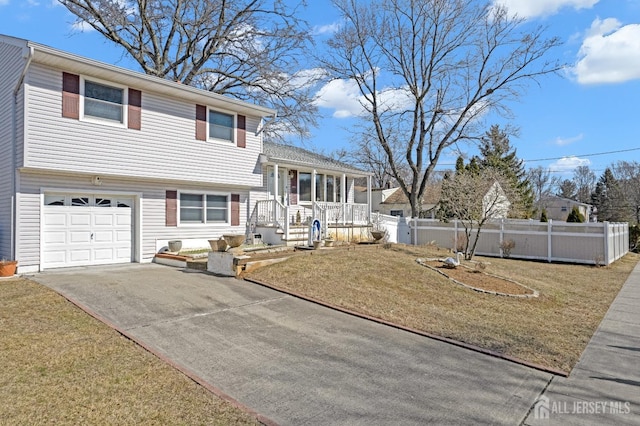 tri-level home with concrete driveway, a front lawn, a porch, and fence