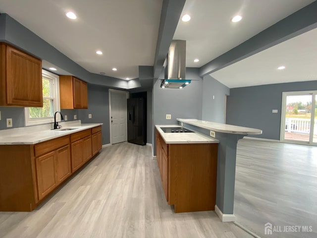 kitchen with beamed ceiling, sink, island exhaust hood, black appliances, and light wood-type flooring