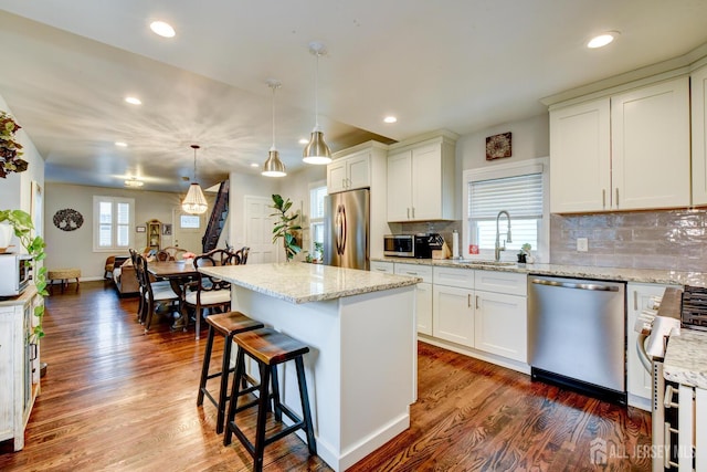 382 Highland St, South Amboy, NJ 08879 - kitchen with appliances with stainless steel finishes, tasteful backsplash, a kitchen bar, dark wood-type flooring, and a center island