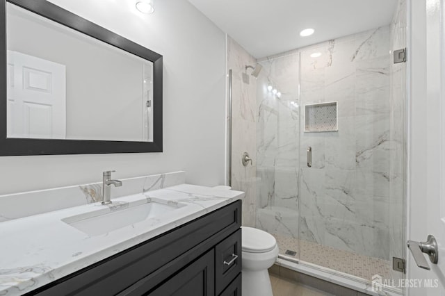 bathroom with vanity, toilet, and a shower with door