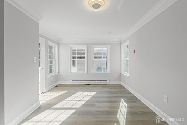 spare room with baseboard heating, crown molding, and light hardwood / wood-style floors