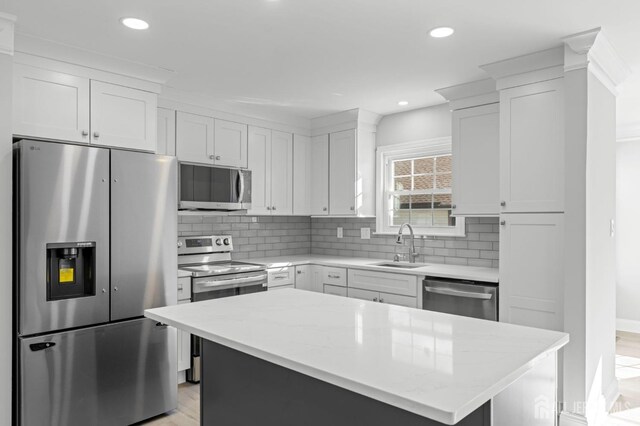 kitchen with white cabinetry, a center island, stainless steel appliances, and sink