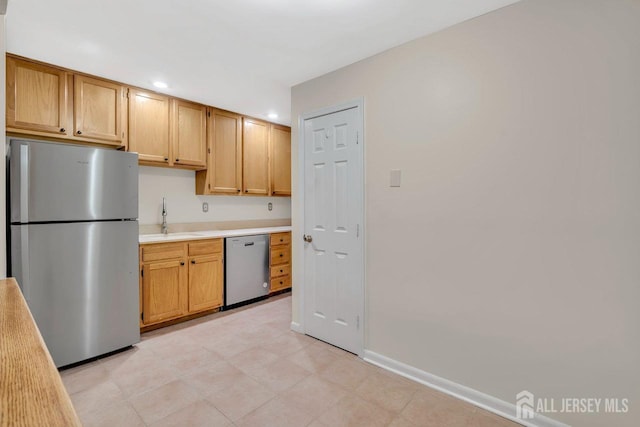 kitchen with a sink, appliances with stainless steel finishes, light countertops, baseboards, and recessed lighting