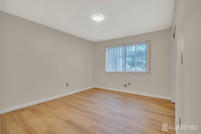 unfurnished room featuring light wood finished floors, visible vents, and baseboards