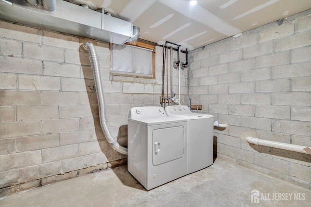 laundry room with concrete block wall, washer and dryer, and laundry area