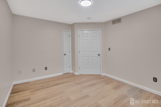 spare room featuring baseboards, visible vents, and light wood-type flooring