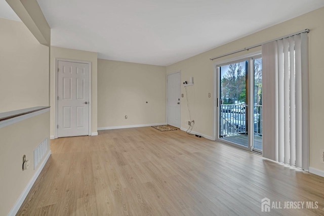 empty room with visible vents, light wood-style flooring, and baseboards