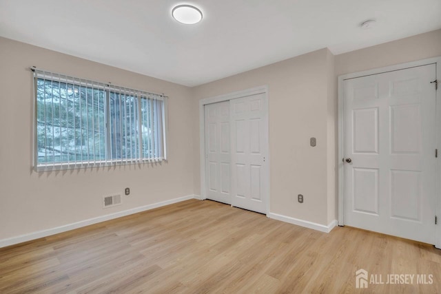 unfurnished bedroom featuring visible vents, a closet, baseboards, and light wood-style floors