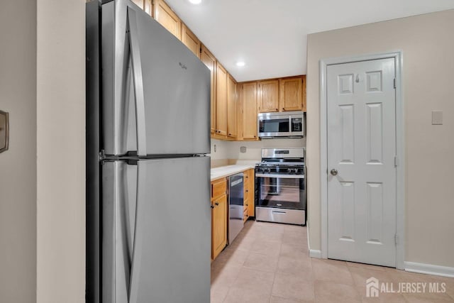 kitchen with baseboards, light tile patterned floors, appliances with stainless steel finishes, and light countertops