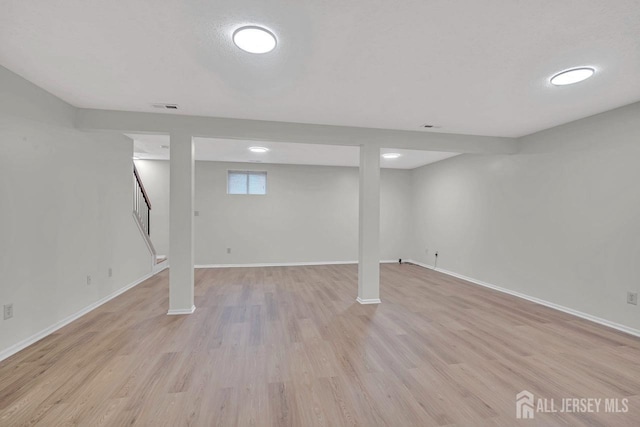 basement featuring stairs, visible vents, light wood-style floors, and baseboards