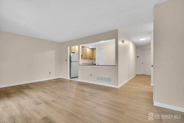unfurnished living room featuring baseboards, visible vents, and light wood-style floors