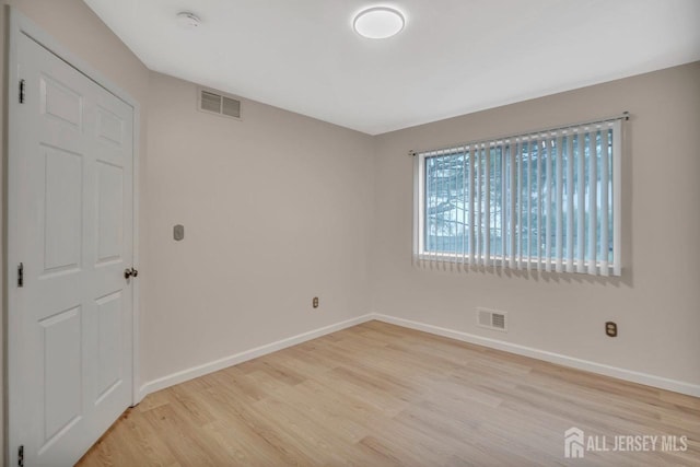 empty room featuring visible vents, baseboards, and light wood-style floors