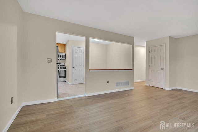interior space featuring visible vents, light wood-style flooring, and baseboards