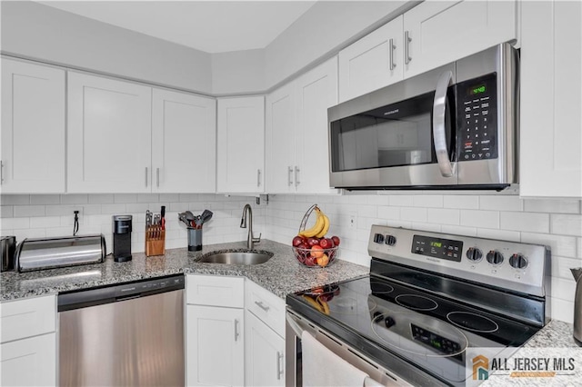 52 Lantern Ln, Sayreville, NJ 08872 - kitchen with appliances with stainless steel finishes, white cabinets, light stone counters, and backsplash