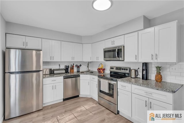 52 Lantern Ln, Sayreville, NJ 08872 - kitchen featuring appliances with stainless steel finishes, light stone counters, white cabinetry, and tasteful backsplash
