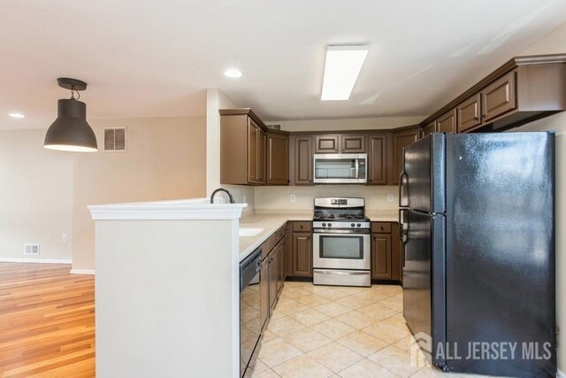 kitchen featuring black appliances, dark brown cabinetry, and hanging light fixtures