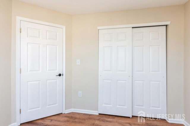 unfurnished bedroom with a closet and wood-type flooring