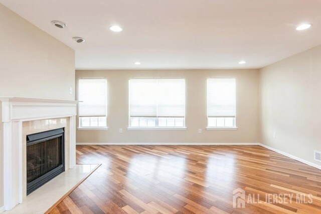 unfurnished living room featuring light hardwood / wood-style flooring and a tiled fireplace