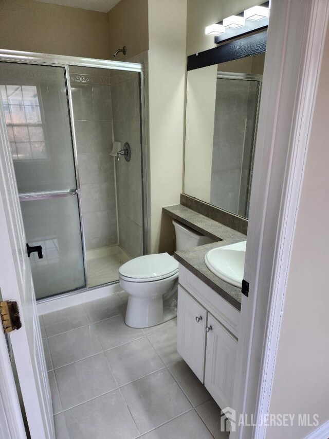 bathroom with tile patterned flooring, vanity, an enclosed shower, and toilet