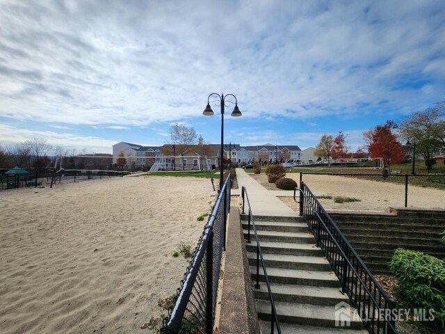 surrounding community with volleyball court and a water view