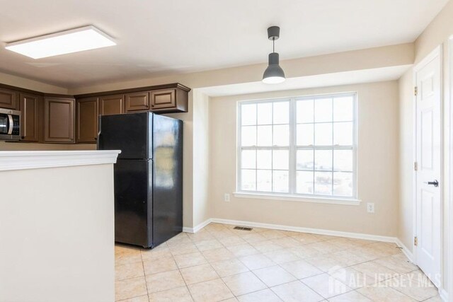 kitchen with black fridge, dark brown cabinets, and hanging light fixtures