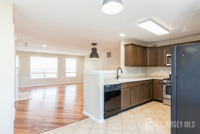 kitchen featuring dark brown cabinets, sink, black appliances, hanging light fixtures, and light tile patterned flooring