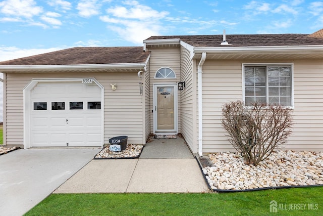 single story home featuring roof with shingles, driveway, and an attached garage