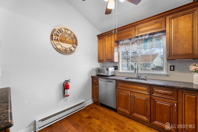 kitchen with lofted ceiling, dark wood-style floors, stainless steel dishwasher, a baseboard heating unit, and a sink