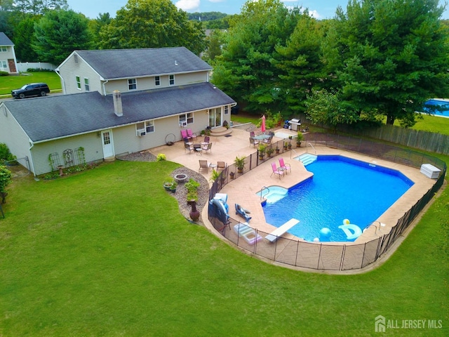 view of swimming pool featuring a lawn, a diving board, and a patio