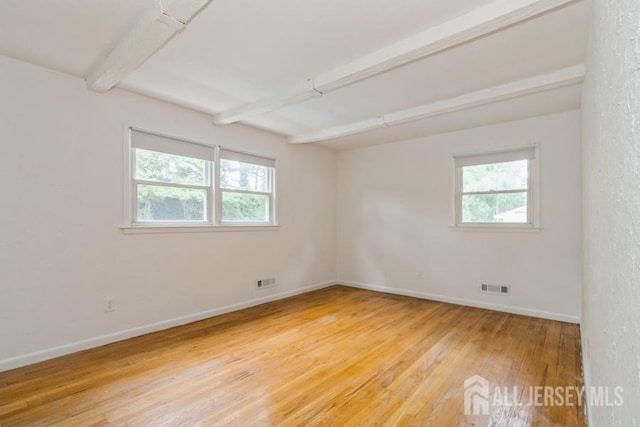 42 Corona Rd, East Brunswick, NJ 08816 - empty room with healthy amount of natural light, beamed ceiling, and light wood-style floors