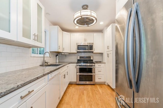 42 Corona Rd, East Brunswick, NJ 08816 - kitchen with stainless steel appliances, light stone countertops, white cabinets, light wood-style flooring, and glass insert cabinets