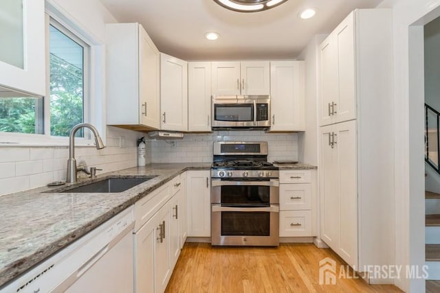 42 Corona Rd, East Brunswick, NJ 08816 - kitchen featuring stainless steel appliances, white cabinetry, light stone countertops, decorative backsplash, and recessed lighting