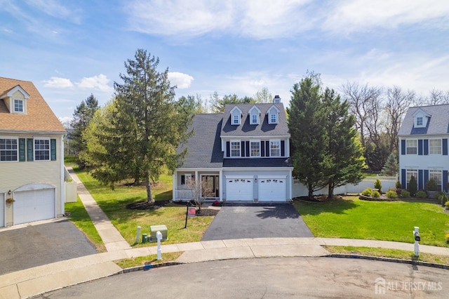 traditional-style house with a garage, a chimney, a front yard, and aphalt driveway