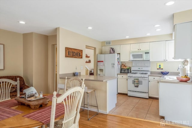 441 Sayre Dr, Plainsboro, NJ 08540 - kitchen featuring white appliances, a peninsula, white cabinetry, light countertops, and recessed lighting