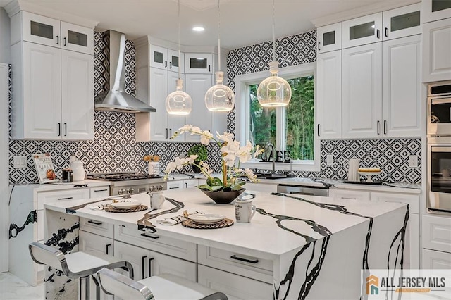 4 Hemlock Dr, Edison, NJ 08820 - kitchen featuring wall chimney range hood, a kitchen island, white cabinetry, a sink, and hanging light fixtures