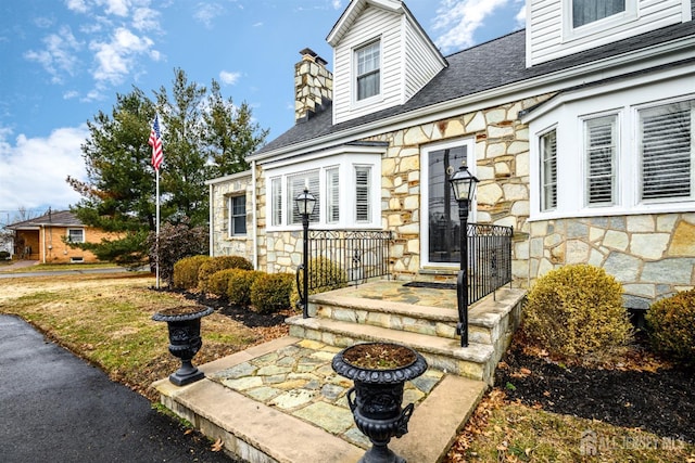 property entrance featuring stone siding and a chimney