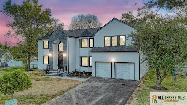 view of front of home featuring aphalt driveway, a front lawn, an attached garage, and stucco siding