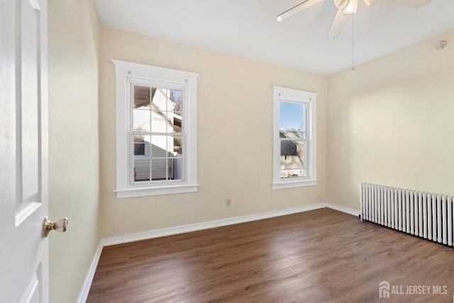 empty room featuring a healthy amount of sunlight, wood finished floors, and radiator