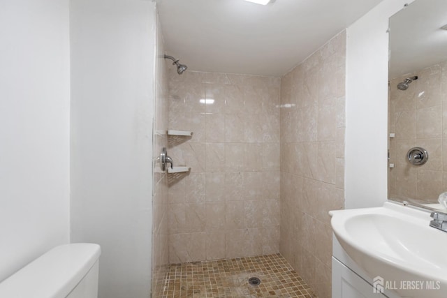 full bathroom featuring tiled shower, vanity, and toilet