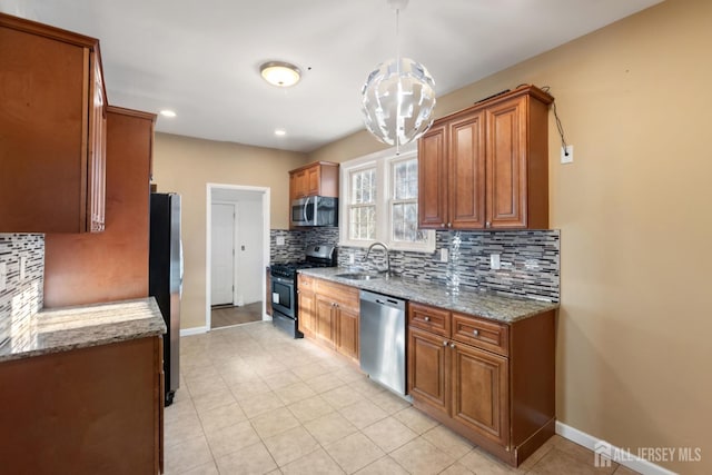 kitchen featuring appliances with stainless steel finishes, a sink, light stone counters, and brown cabinets