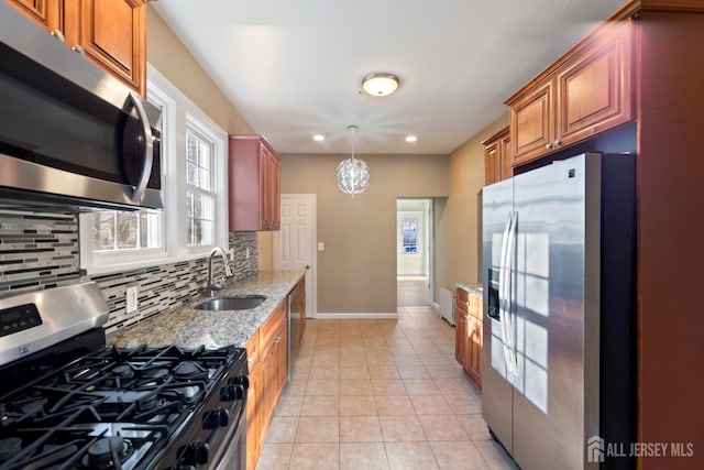 kitchen with light tile patterned floors, stainless steel appliances, a sink, backsplash, and light stone countertops