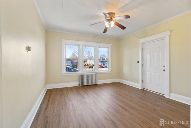 unfurnished room with crown molding, radiator, wood finished floors, and baseboards