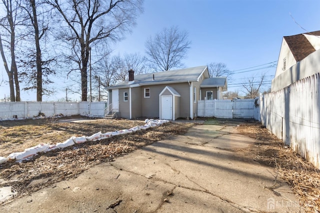 rear view of property featuring a chimney and fence