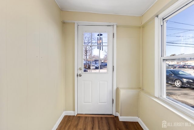 doorway featuring dark wood-type flooring and baseboards