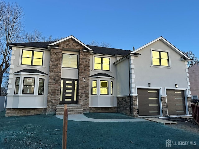 view of front of house featuring a garage, stone siding, and stucco siding