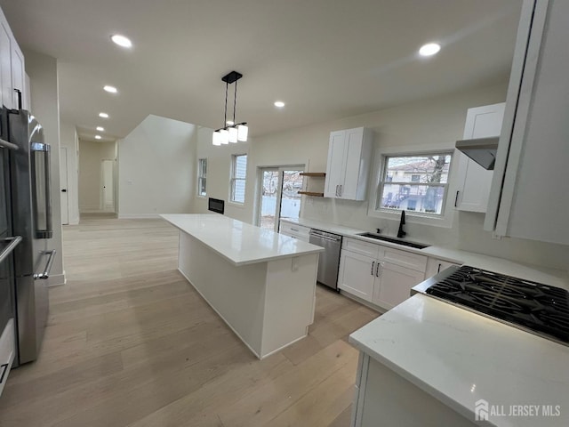 kitchen featuring appliances with stainless steel finishes, sink, a center island, pendant lighting, and white cabinets