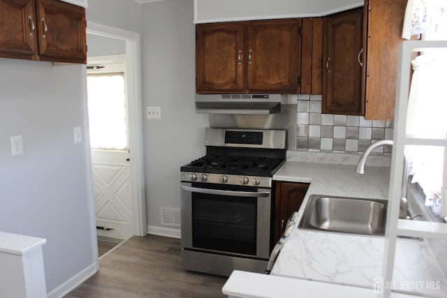 2 Haven Ter, Sayreville, NJ 08859 - kitchen with under cabinet range hood, gas range, a sink, backsplash, and wood finished floors