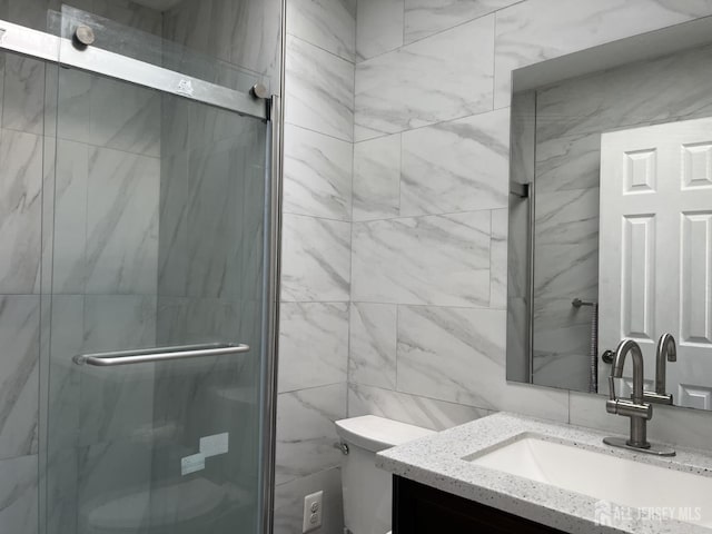 bathroom featuring a stall shower, tile walls, vanity, and toilet