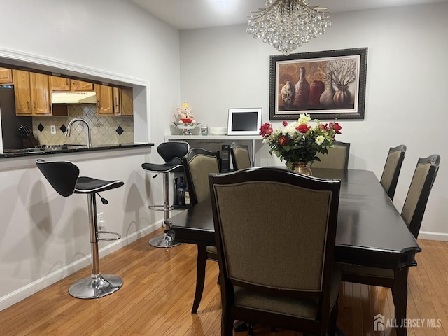 dining room with light wood-style floors, baseboards, and a chandelier