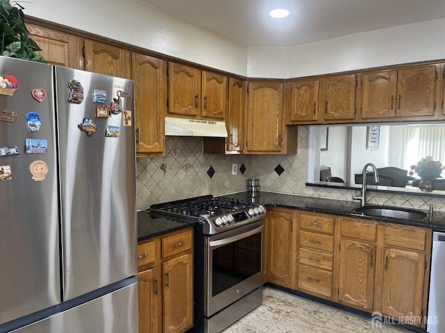 kitchen featuring brown cabinets, decorative backsplash, appliances with stainless steel finishes, a sink, and under cabinet range hood